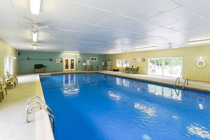 Inviting indoor swimming pool with bright lighting, comfortable seating, and large windows showcasing natural views.