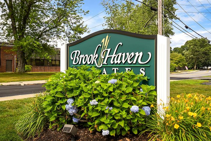 Inviting entrance sign for Brook Haven Estates, surrounded by lush greenery and vibrant flowers, conveying a welcoming and serene residential community.