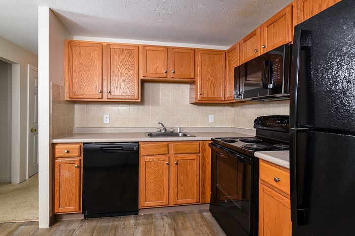 Charming kitchen with rich wooden cabinets, modern black appliances, and sleek countertops, perfect for culinary exploration.
