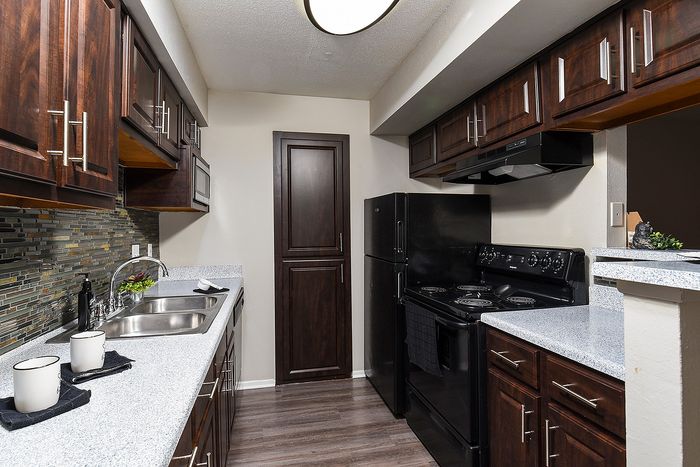 Chic modern kitchen with elegant dark wood cabinets, sleek countertops, and premium appliances, perfect for culinary enthusiasts.