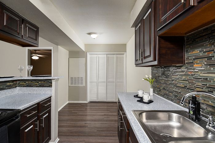 Modern kitchen with sleek countertops, elegant dark wood cabinets, and a stylish mosaic backsplash.