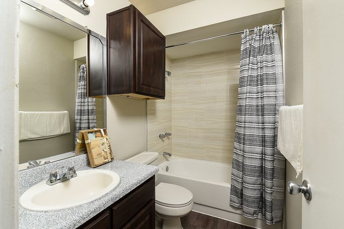Elegant bathroom with modern fixtures, stylish granite countertop, and chic patterned shower curtain.