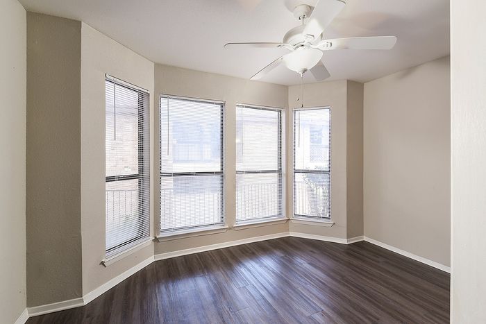 Bright corner room with elegant hardwood floors and expansive windows, allowing natural sunlight to create a warm and inviting space.