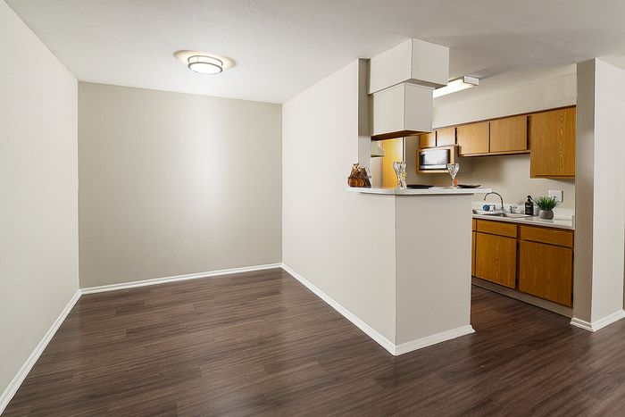 Modern apartment with open dining area and sleek kitchen featuring wood cabinets and stylish lighting.
