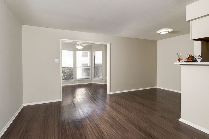 Spacious open-plan living area with elegant hardwood floors and large windows inviting natural light.