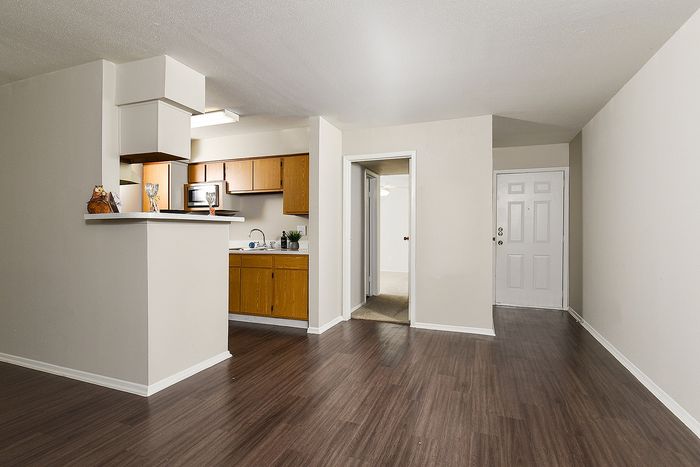 Modern apartment interior featuring an open kitchen with sleek wooden cabinetry and an inviting living area with elegant flooring.