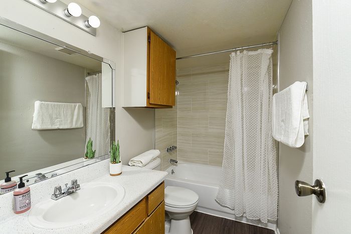 Elegant bathroom showcasing modern fixtures, a large mirror, and a stylish shower with a pristine white curtain.