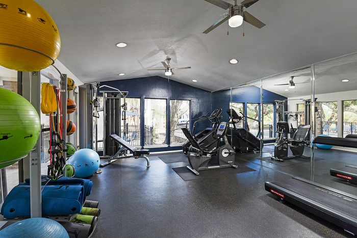 Modern fitness center with state-of-the-art equipment, vibrant exercise balls, and large windows for natural light.