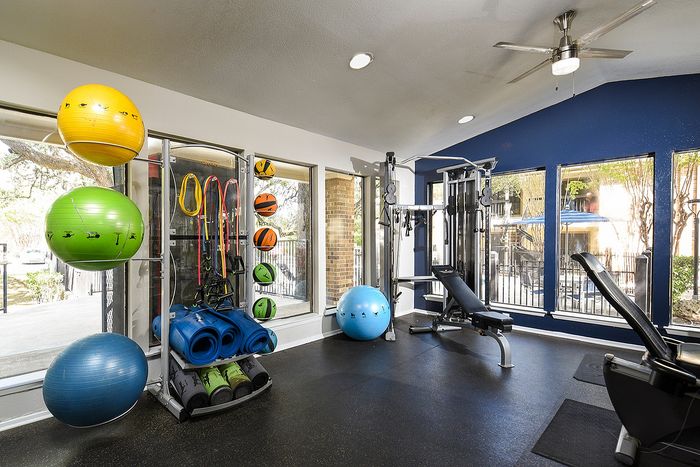 Bright and modern fitness center featuring exercise balls, resistance bands, and a multi-use weight machine, perfect for an active lifestyle.
