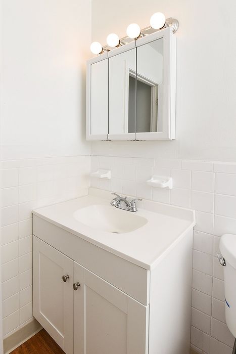 Modern bathroom with elegant white vanity, mirrored cabinet, and bright lighting fixtures, creating a fresh and inviting space.