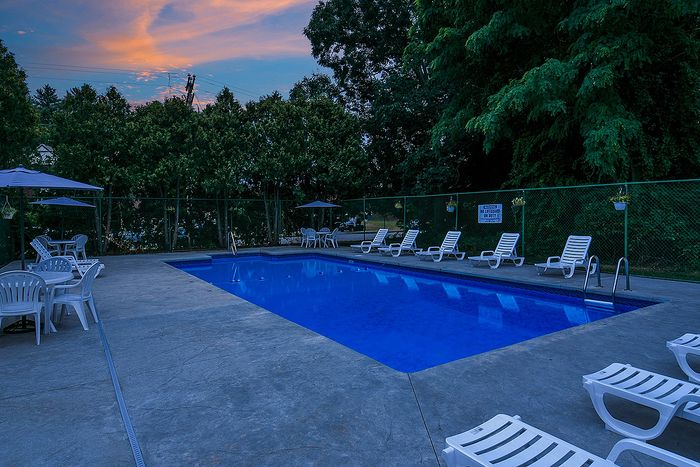 Inviting outdoor pool area with lounge chairs, surrounded by lush greenery and a serene evening sky.