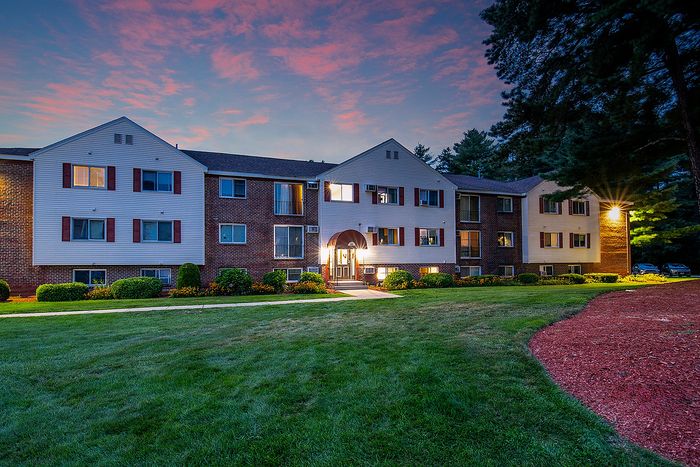 Charming apartment complex with welcoming entrance, beautifully landscaped garden, and tranquil evening ambiance.