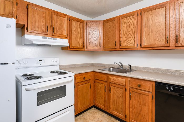 Charming kitchen with warm wooden cabinetry, modern appliances, and sleek countertops offering a cozy culinary experience.
