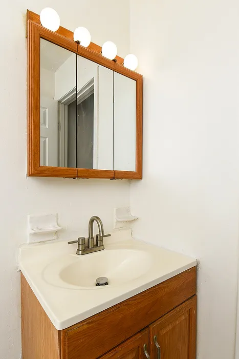 Chic bathroom vanity with elegant wooden cabinet, sleek mirror, and modern lighting fixtures.