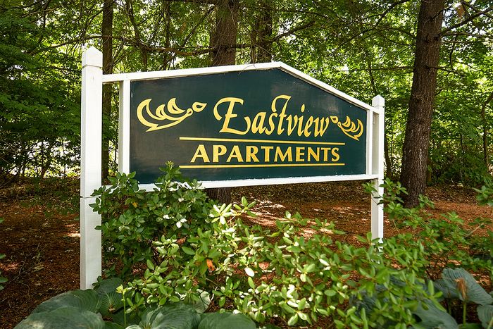 Inviting Eastview Apartments sign nestled among lush greenery, promising tranquil living in a serene natural setting.