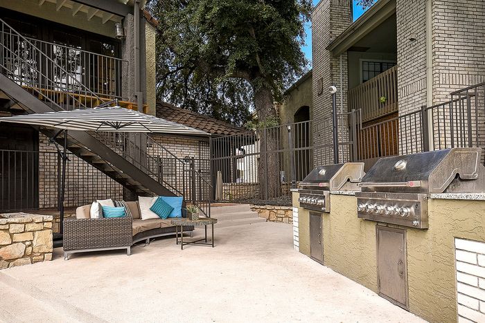 Inviting outdoor patio with cozy seating, stylish umbrella, and dual stainless steel grills, perfect for entertaining and relaxation.