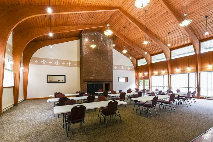 Elegant community room with high wooden ceilings, ample natural light, and a cozy brick fireplace, perfect for gatherings.