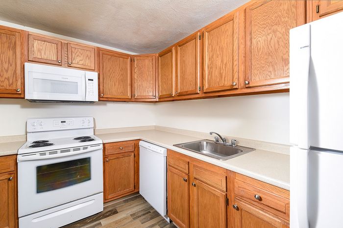 Charming kitchen with warm wooden cabinetry, sleek countertops, and modern appliances including a microwave and dishwasher.