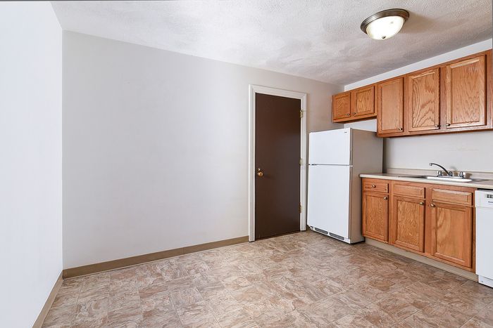 Bright and inviting kitchen with modern wooden cabinetry, sleek countertops, and a white refrigerator. Ideal for culinary creativity and everyday dining.