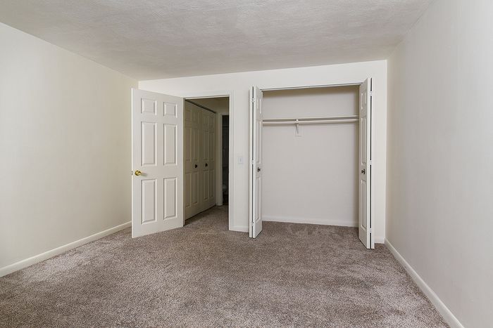 Inviting bedroom featuring plush carpet, ample closet space, and a neutral color palette perfect for customization.
