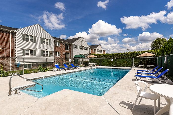 Inviting apartment pool area with sun loungers, surrounded by charming residential buildings, perfect for relaxation and enjoyment.