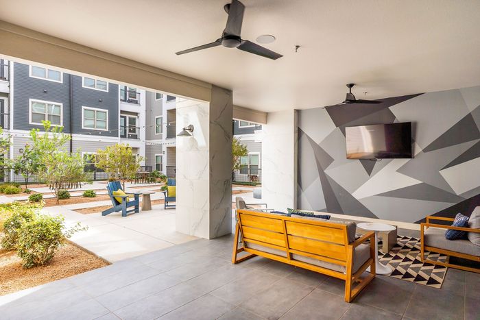 Chic outdoor lounge area with modern seating, vibrant geometric wall art, and lush courtyard view.