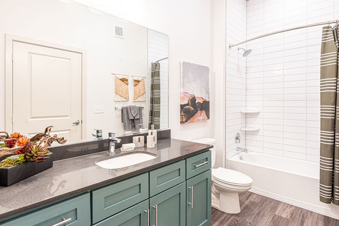 Chic bathroom with modern fixtures, stylish green cabinetry, and elegant tile accents, highlighting a luxurious ambience.