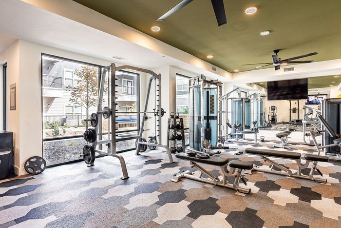 Modern and inviting apartment gym featuring state-of-the-art fitness equipment, large mirrors, and ample natural light.