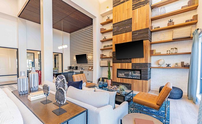 Modern living room with high ceilings, elegant shelving, stylish decor, and a sleek fireplace, creating a cozy yet sophisticated ambiance.