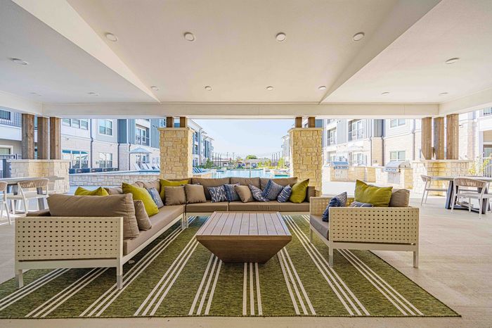 Elegant outdoor lounge with plush seating, stylish decor, and vibrant poolside view at a modern apartment community.