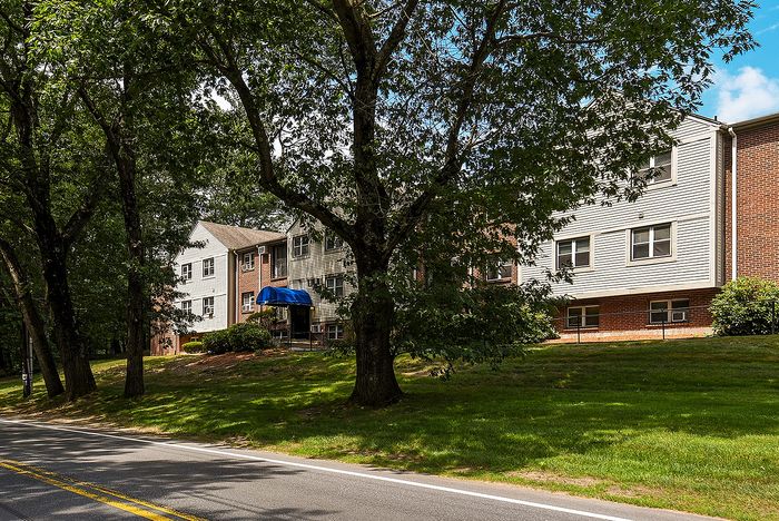 Charming multi-story apartment building nestled amid lush green trees, offering a tranquil and picturesque living environment.
