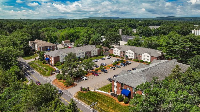 Charming apartment complex surrounded by lush greenery, offering ample parking and a serene environment for modern living.