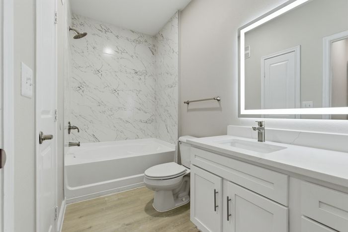 Elegant bathroom with marble-tiled walls, sleek vanity, and modern LED mirror lighting.