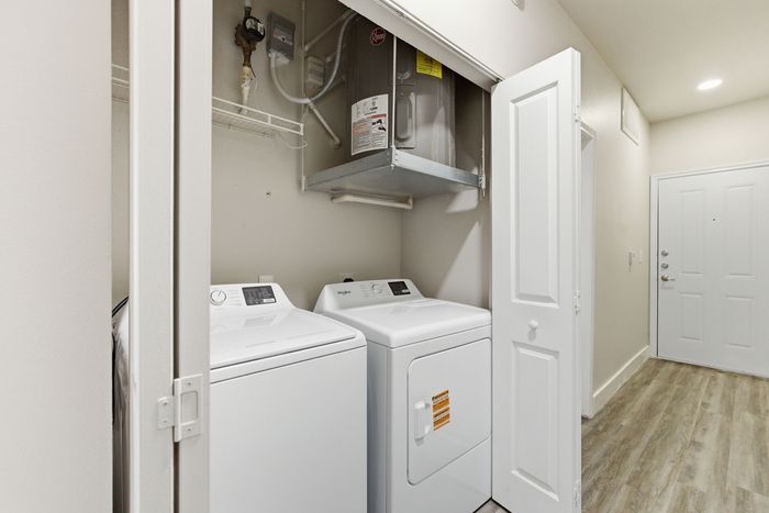 Contemporary apartment hallway featuring an in-unit laundry area with modern washer and dryer, complemented by sleek flooring and neutral decor.