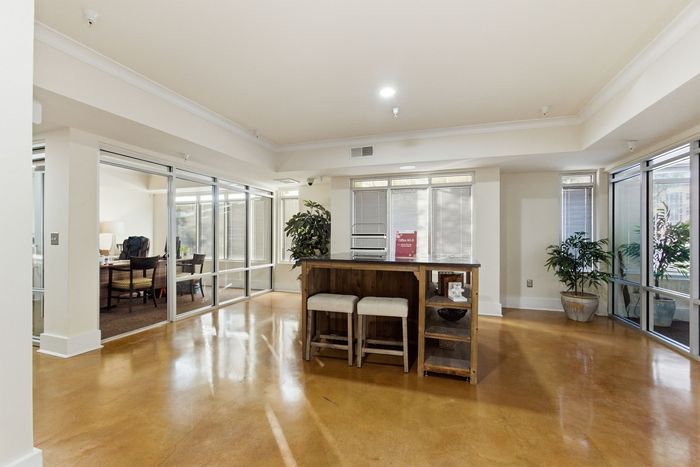 Bright and spacious communal area with sleek glass partitions, warm wood accents, and inviting seating.
