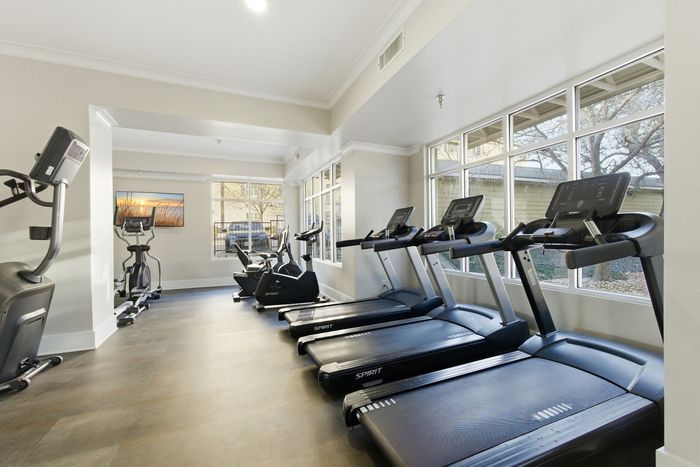 Bright and modern fitness center with state-of-the-art treadmills and exercise bikes, complemented by large windows for natural light.