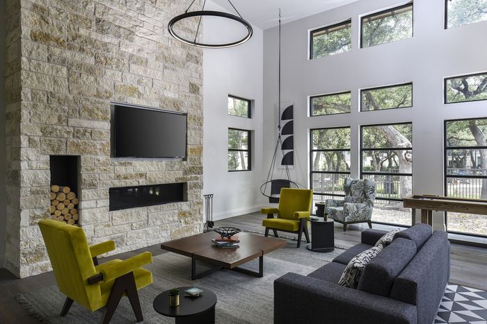 Luxurious living room featuring a stone fireplace, vibrant modern seating, and large windows overlooking serene greenery.