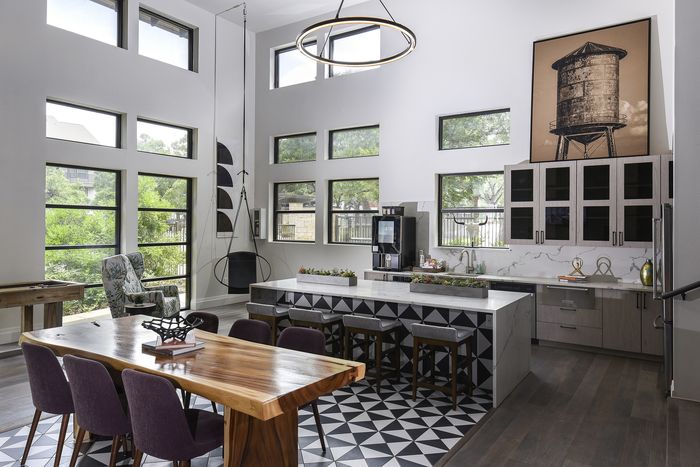 Chic modern kitchen with high ceilings, large windows, and stylish geometric flooring, featuring a spacious island and elegant furnishings.