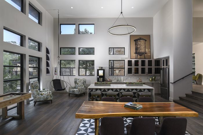 Spacious open-concept living area with high ceilings, modern kitchen, stylish seating, and large windows for natural light.