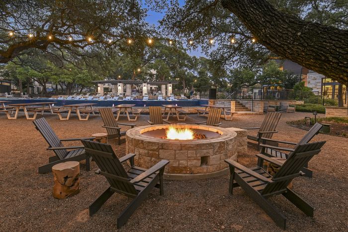 Charming outdoor community area featuring a cozy fire pit, surrounded by ample seating and illuminated string lights, perfect for evening gatherings.