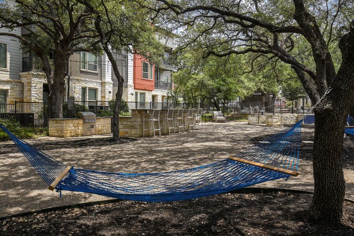 Charming outdoor relaxation area with blue hammocks, modern seating, and lush greenery perfect for unwinding.