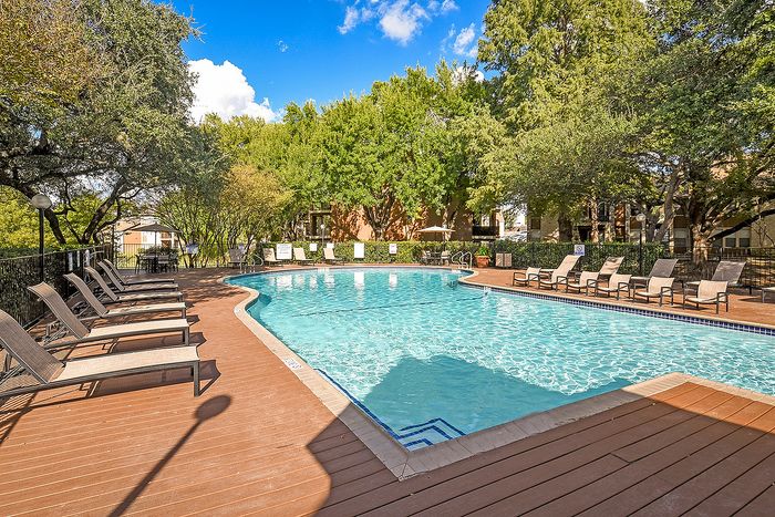 Inviting outdoor swimming pool surrounded by lush greenery and comfortable lounge chairs, perfect for relaxation and leisure.