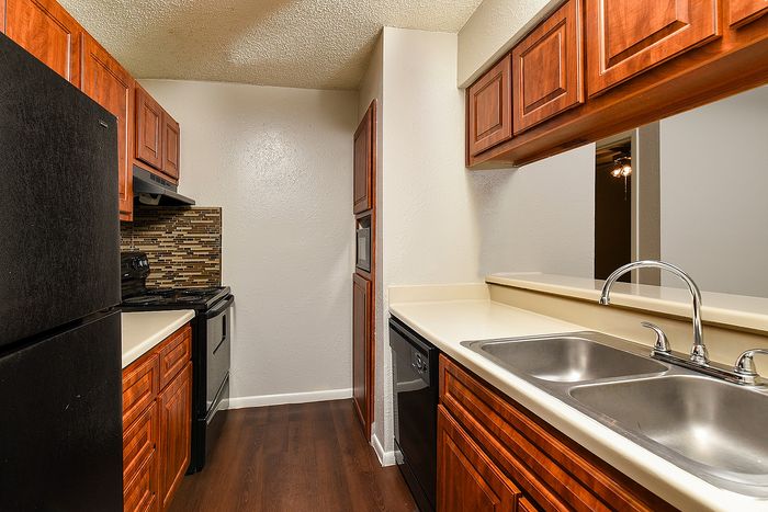 Charming kitchen with sleek black appliances, warm wooden cabinetry, and modern tile backsplash.