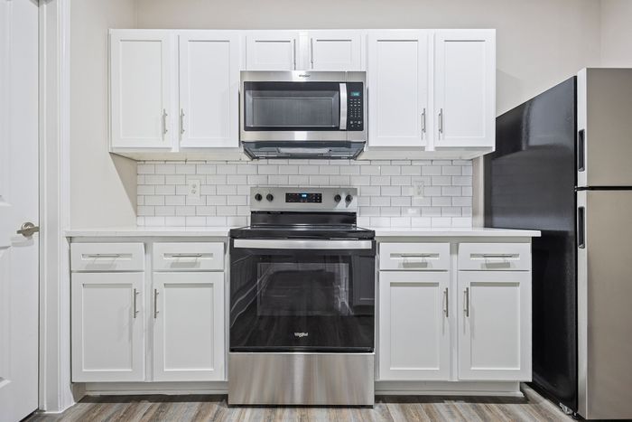 Modern kitchen with sleek stainless steel appliances, elegant white cabinetry, and stylish subway tile backsplash.