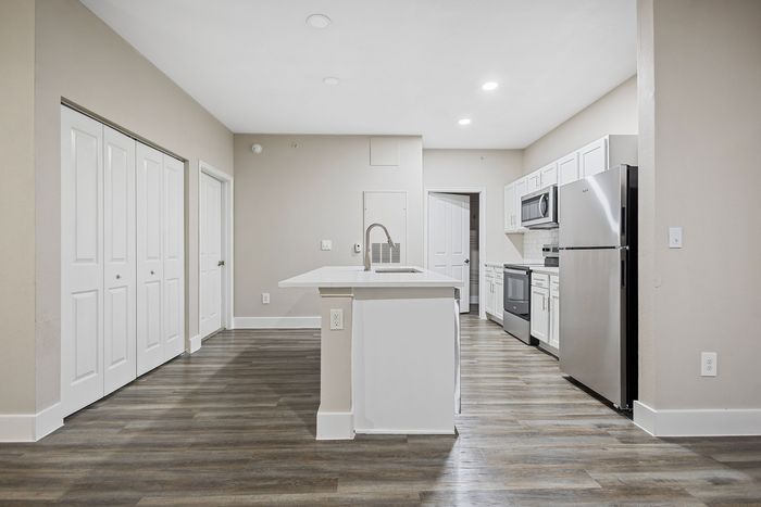 Modern kitchen with sleek stainless steel appliances, spacious island, and elegant cabinetry on polished wood flooring.