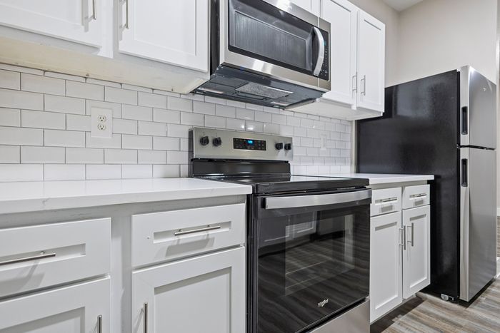 Modern kitchen with sleek stainless steel appliances, white cabinetry, and elegant subway tile backsplash.