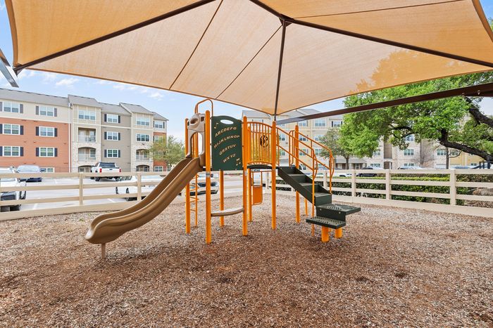 Inviting apartment complex playground featuring vibrant slides and shaded play area for a perfect family-friendly environment.