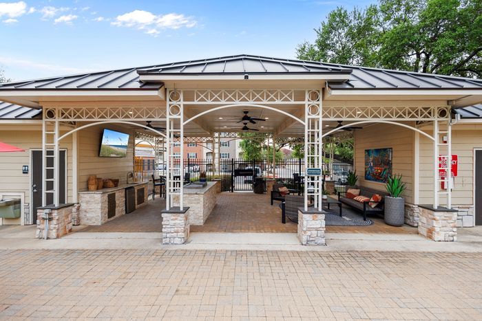 Charming outdoor pavilion with elegant lattice design, featuring comfortable seating and a stylish outdoor kitchen area, perfect for entertaining.