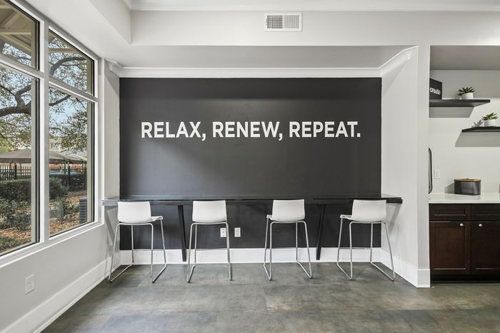 Bright and inviting study nook with modern seating and motivational wall art reading 'Relax, Renew, Repeat'.