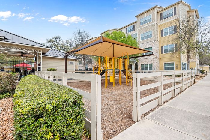 Inviting apartment community with vibrant playground and lush greenery, perfect for families.